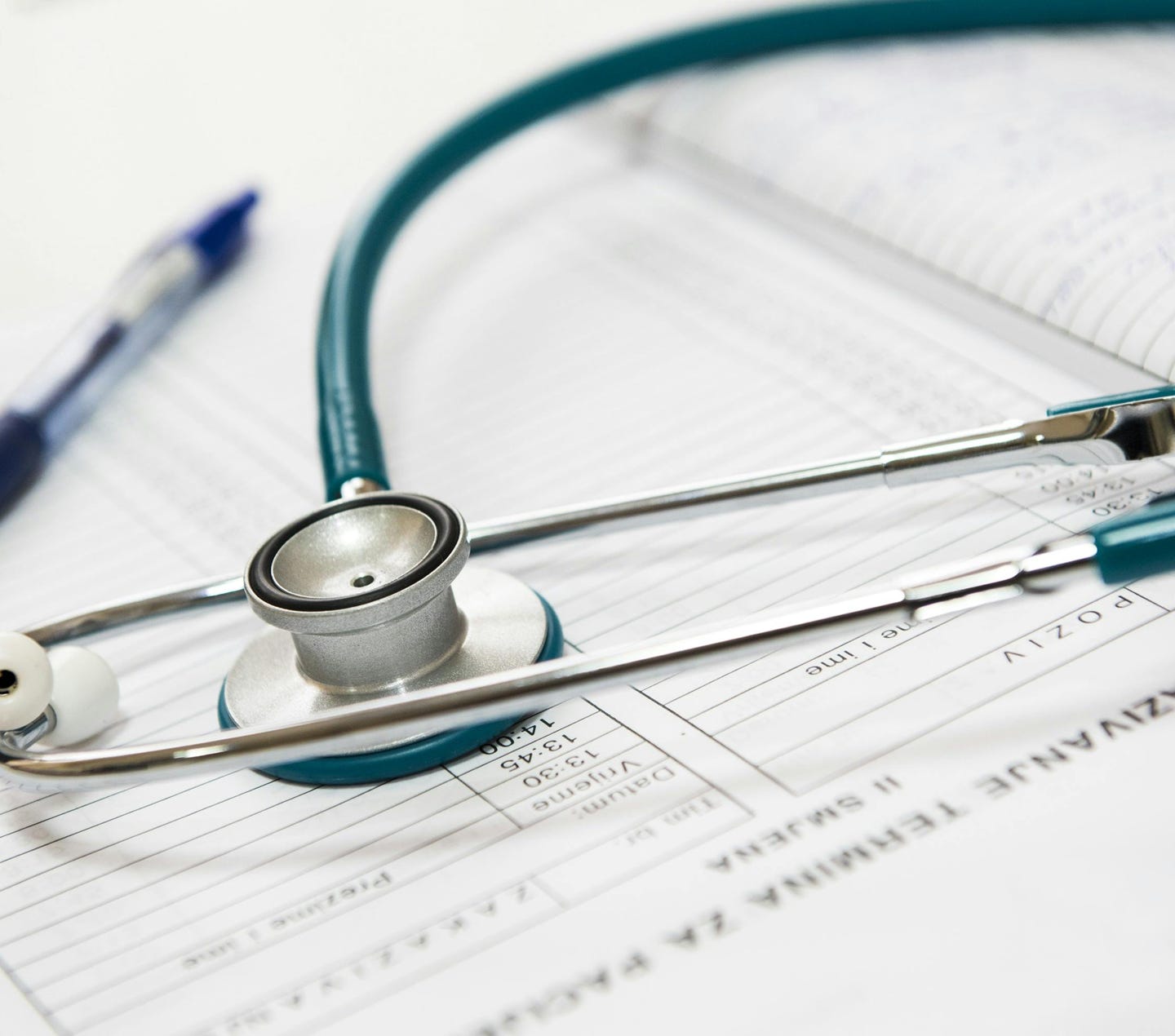 A stethoscope and pen resting on a medical report in a healthcare setting.