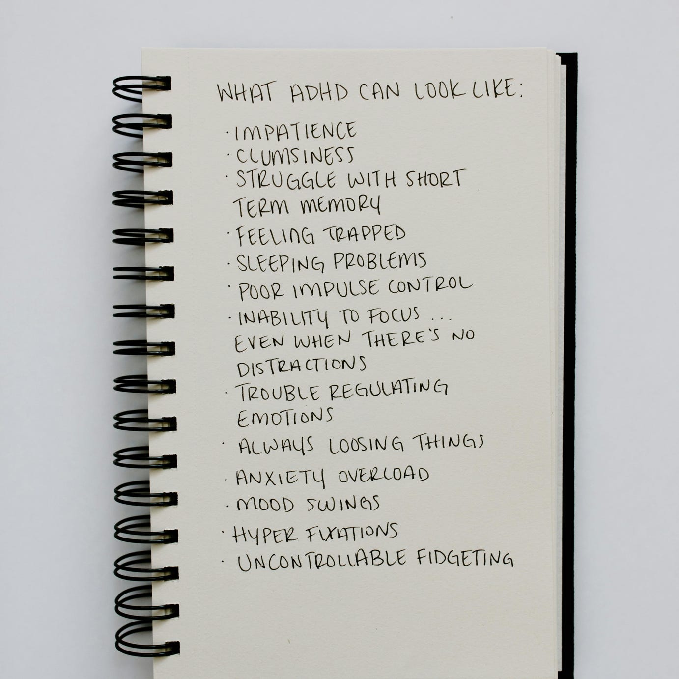 Spiral notepad listing ADHD symptoms, highlighting mental health awareness.