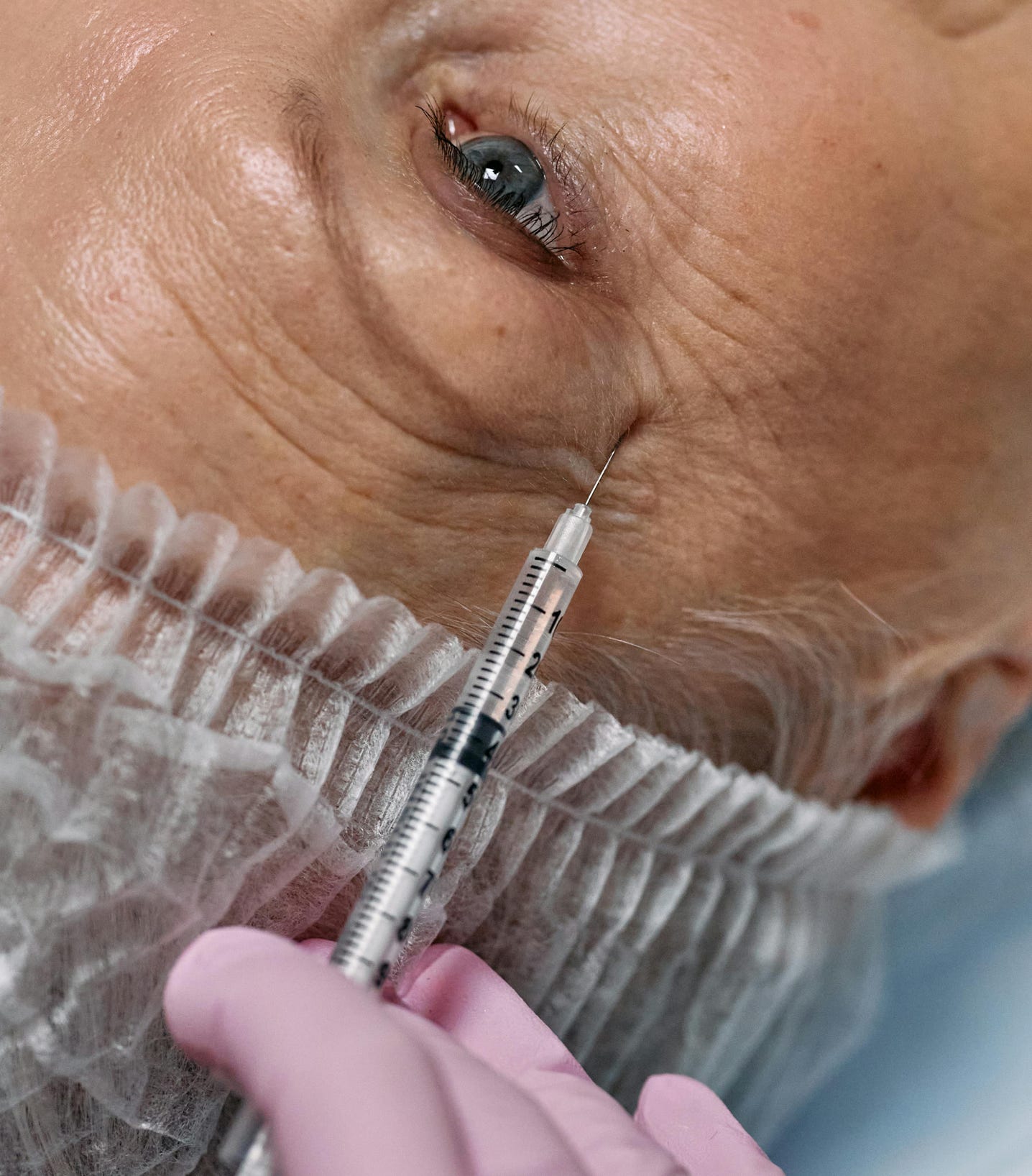 Close-up view of a senior woman receiving an anti-aging facial injection in a clinic.